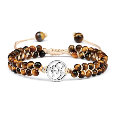 Stack of tiger eye beaded bracelets with a silver charm on a white background