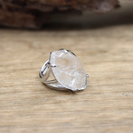 Silver ring with a large, rough-cut gemstone on a wooden surface
