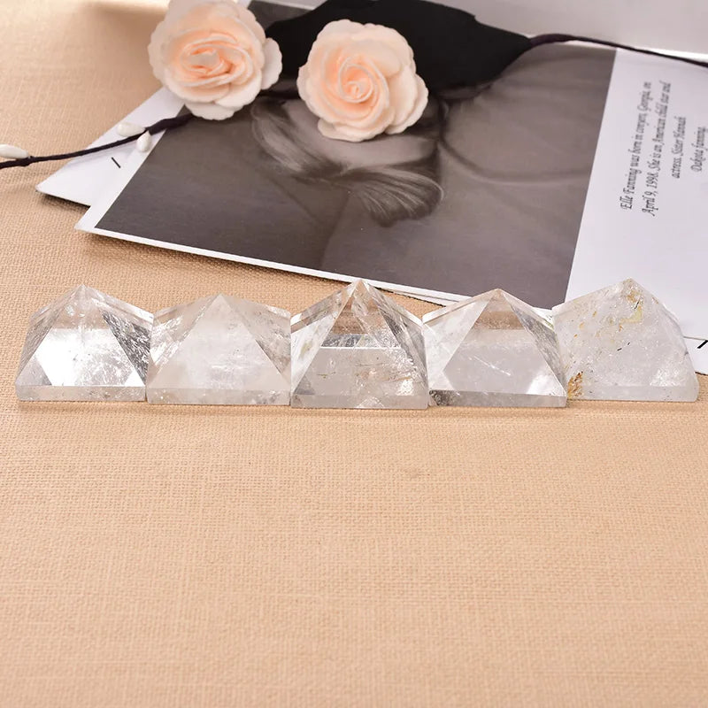 Crystal pyramids on a beige surface with a black and white photo and flowers in the background