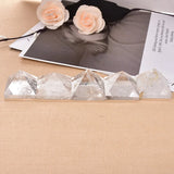 Crystal pyramids on a beige surface with a black and white photo and flowers in the background