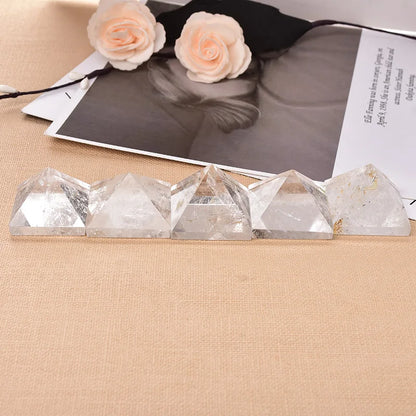 Crystal pyramids on a beige surface with a black and white photo and flowers in the background