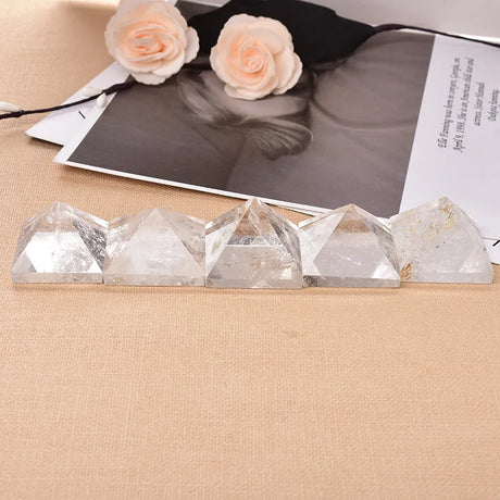 Crystal pyramids on a beige surface with a black and white photo and flowers in the background
