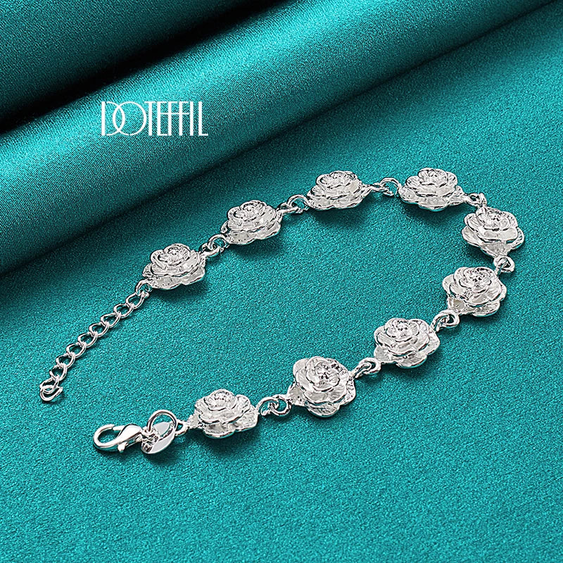 Silver bracelet with floral designs on a teal fabric background