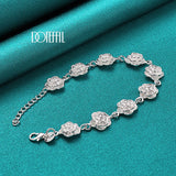 Silver bracelet with floral designs on a teal fabric background