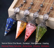 Four crystal pendulums with colored stones on a wooden surface, branded 'Cristal Jewelry'.