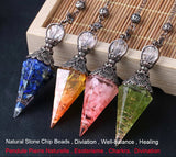 Four crystal pendulums with colored stones on a wooden surface, branded 'Cristal Jewelry'.