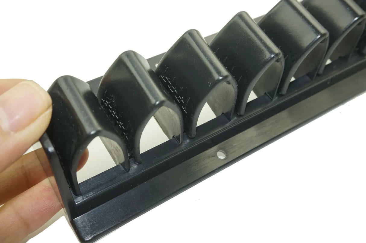 Black plastic tool with multiple components held by a hand on a white background