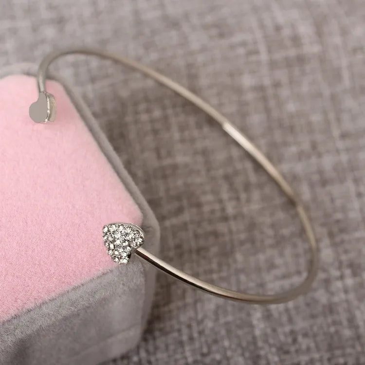 Gold bracelet with a heart-shaped clasp on a textured surface
