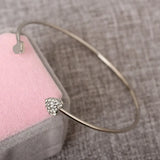 Gold bracelet with a heart-shaped clasp on a textured surface