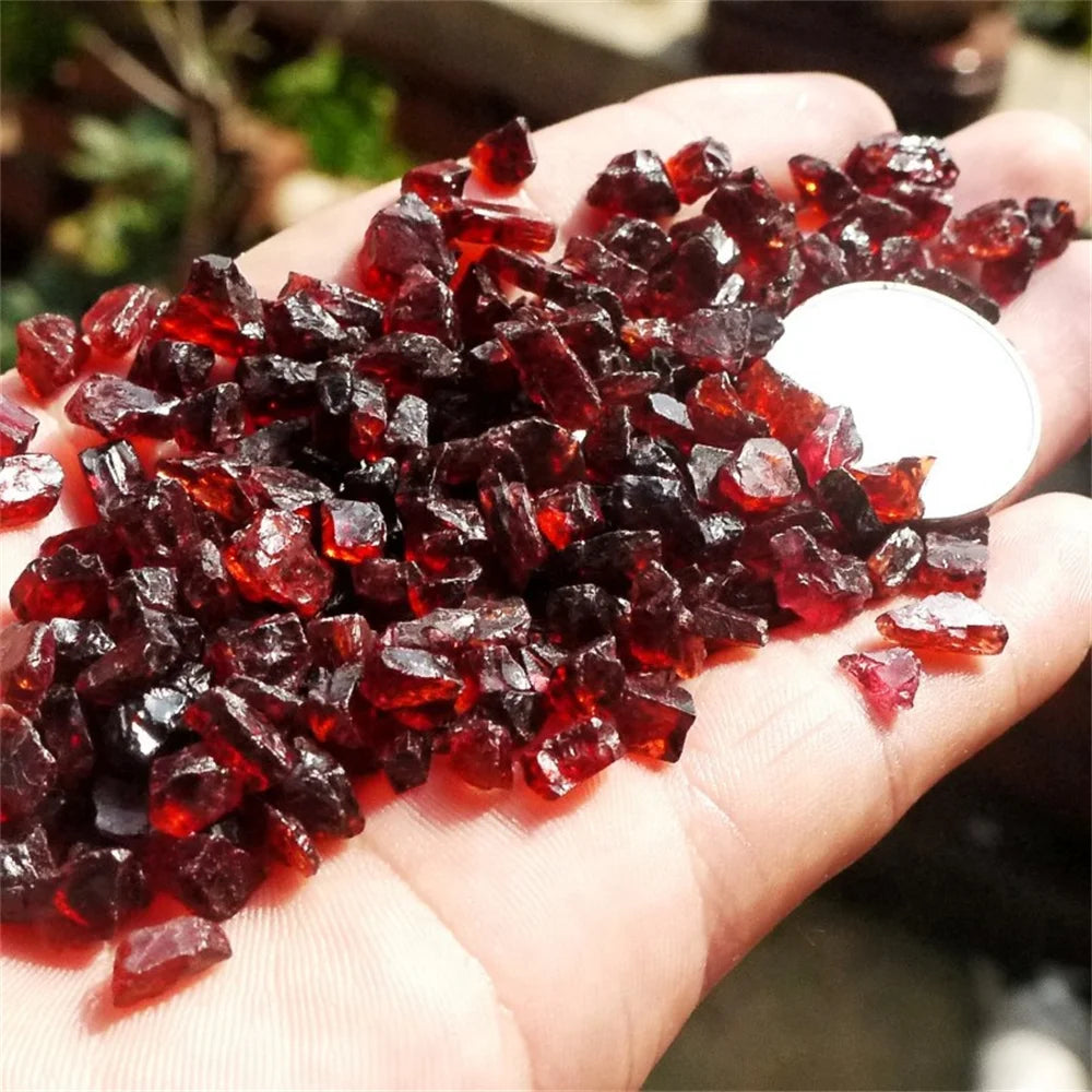 Hand holding red gemstones with a blurred natural background
