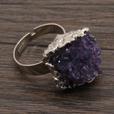 Ring with purple geode stone on a wooden surface