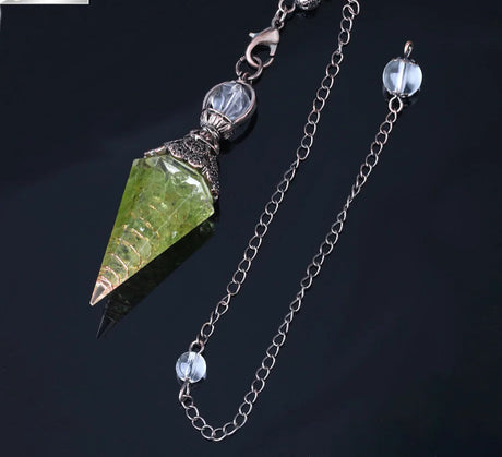 Jewelry with green crystal pendant and chain on a dark background