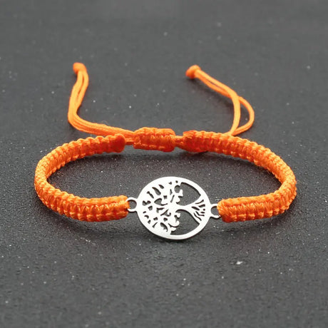 Orange braided bracelet with a silver tree-of-life charm on a dark background