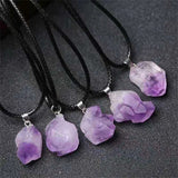 Purple crystal pendants on black cords against a dark background