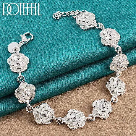 Silver floral bracelet on a textured blue and brown surface with 'Doteefil' branding.
