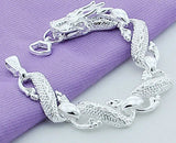 Silver bracelet with dragon design on a purple fabric background