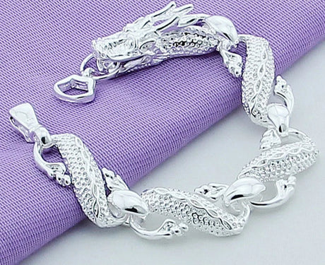 Silver bracelet with dragon design on a purple fabric background