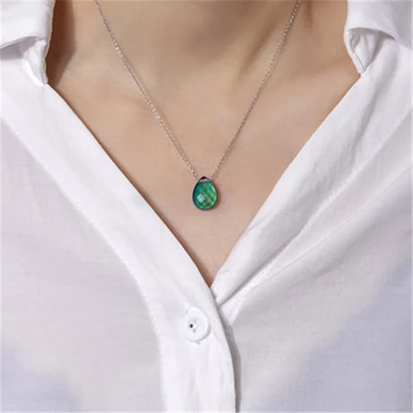 Green teardrop pendant necklace on a white shirt