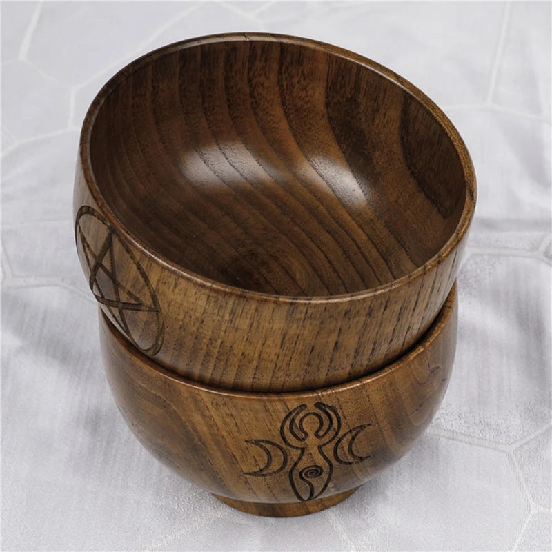 Two wooden bowls with engraved designs on a white textured background
