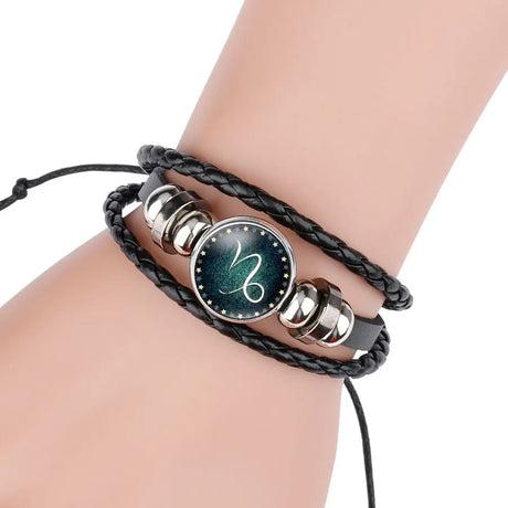 Bracelet with black braided strap and silver and black circular charms on a wrist.