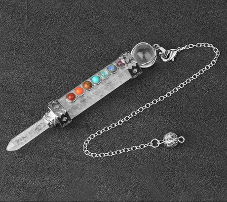 Decorative dagger with gemstones on a chain against a dark background
