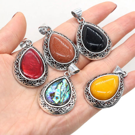 Five colorful stone pendants on a hand with a white background