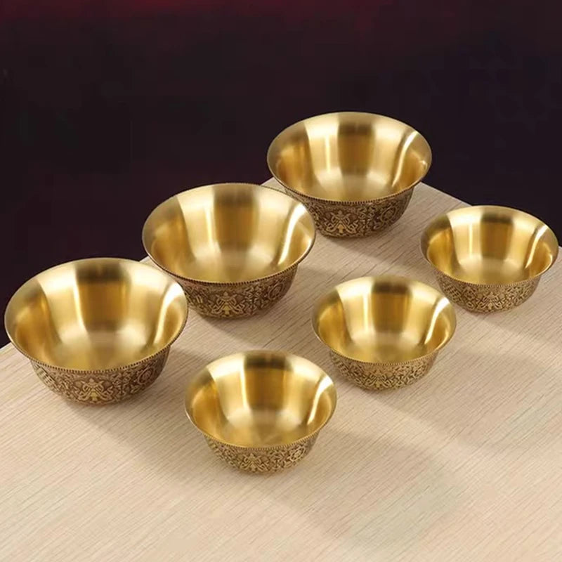 Set of six gold bowls with intricate patterns on a beige surface.