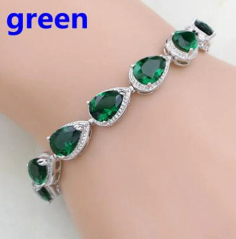 Silver bracelet with green gemstones on a white background