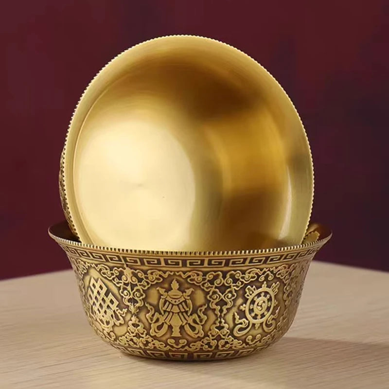 Decorative gold bowl with intricate patterns on a wooden surface against a dark background