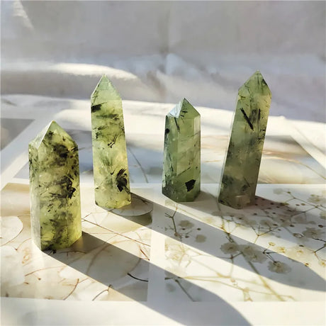 Four green crystal points on a marble surface with floral patterns