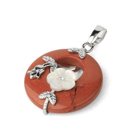 Jewelry pendant with red stone and silver floral design on a white background