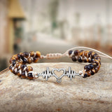 Beaded bracelet with a heart rate design on a stone surface
