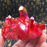 Red crystal cluster held in a hand with a dark background