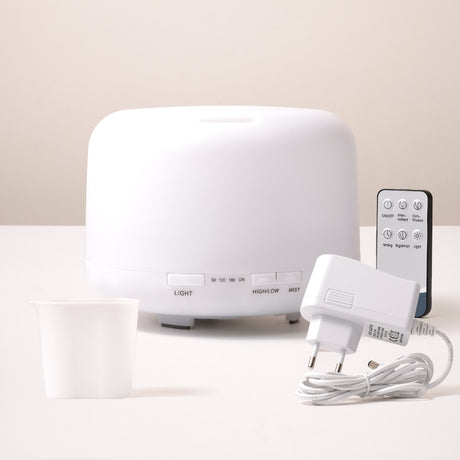 White humidifier with remote control and power adapter on a light background