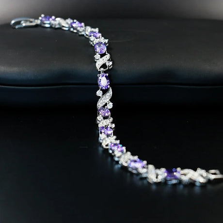 Silver bracelet with purple gemstones on a black surface