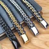 Set of leather and metal dog collars in black, gold, and silver on a wooden surface.