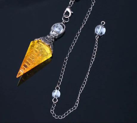 Jewelry with a yellow gemstone and silver chain on a dark background