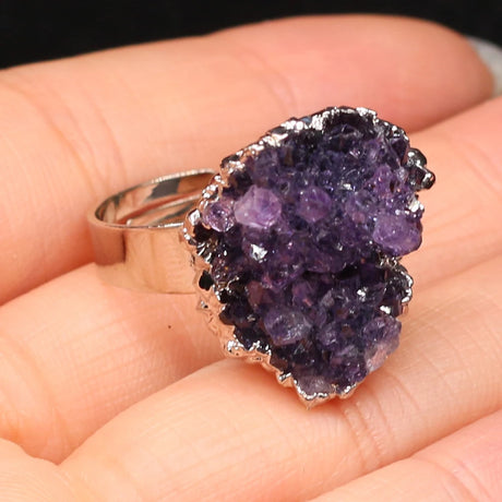 Amethyst ring held in a hand against a neutral background