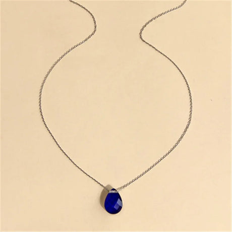 Necklace with a blue teardrop pendant on a beige background