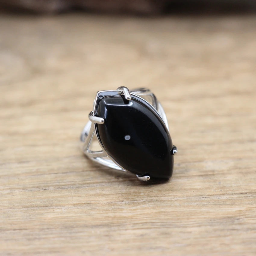 Silver ring with a large black stone on a wooden surface
