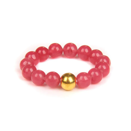 Pink beaded bracelet with a gold focal bead on a white background