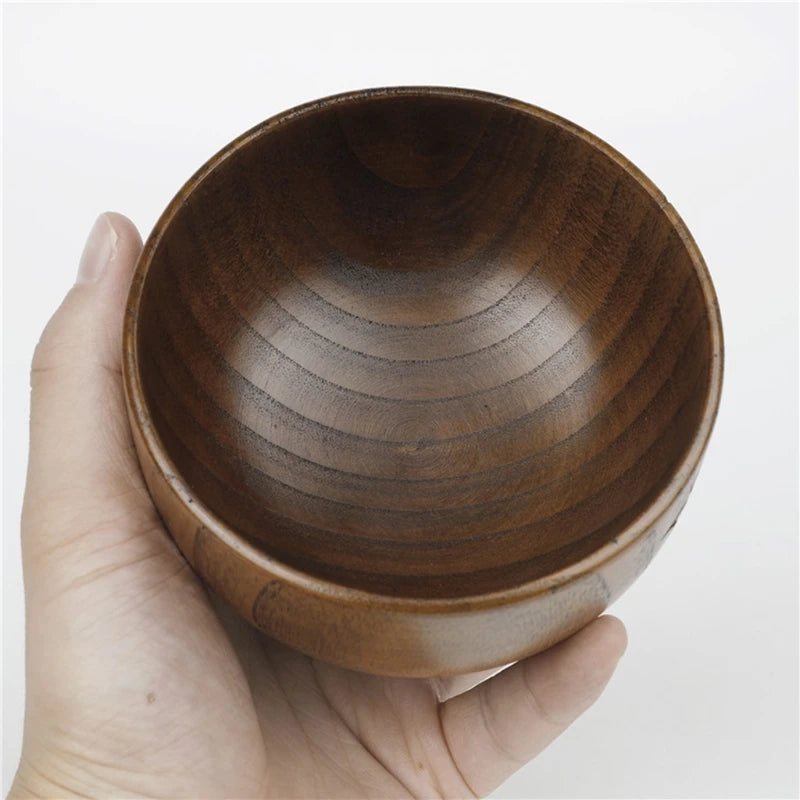 Hand holding a wooden bowl against a white background