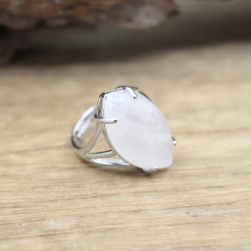 Silver ring with a large white stone on a wooden surface