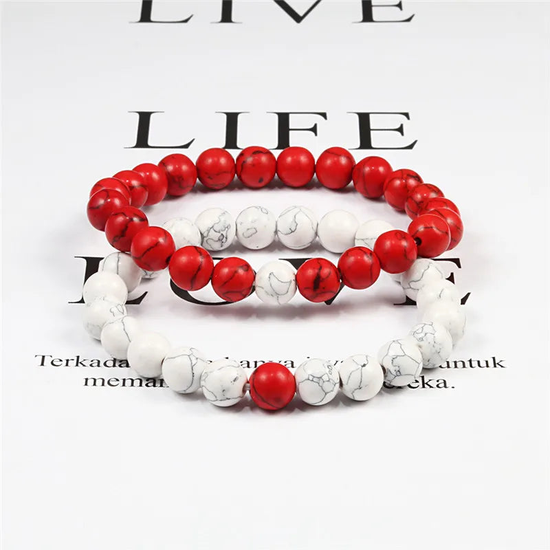 Two beaded bracelets, one red and one white, on a magazine background with visible text.