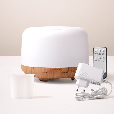 White and wooden diffuser with remote control and power adapter on a light background