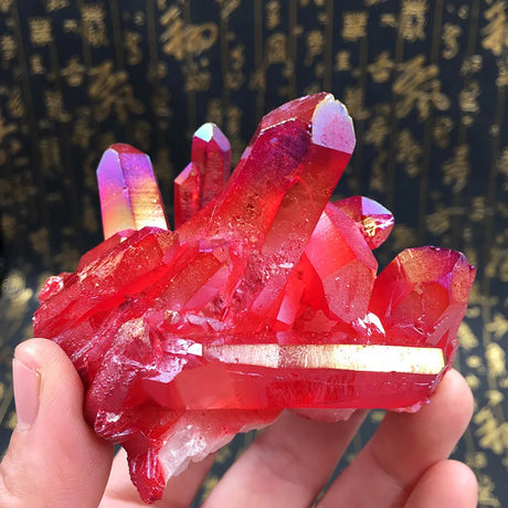 Red crystal formation held in a hand with a blurred background