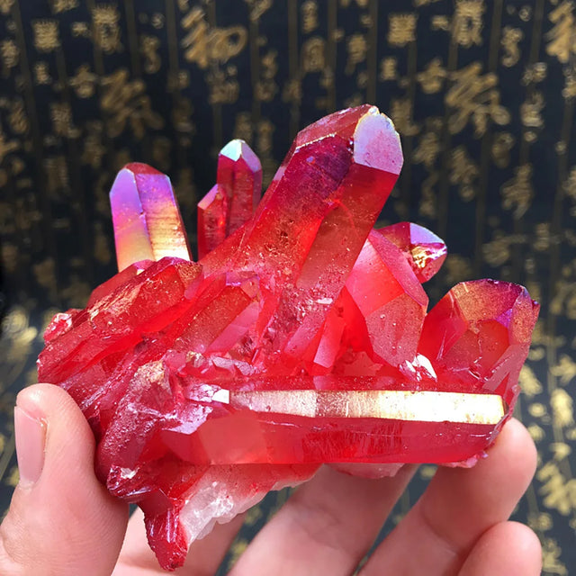 Red crystal formation held in a hand with a blurred background