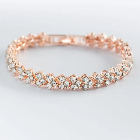 Rose gold bracelet with clear stones on a light gray background