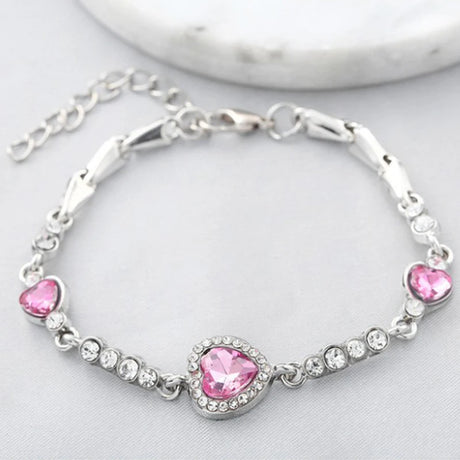 Silver bracelet with pink heart-shaped stones on a light background
