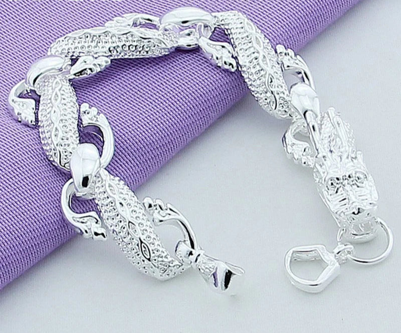 Silver bracelet on a light gray background with a purple fabric underneath